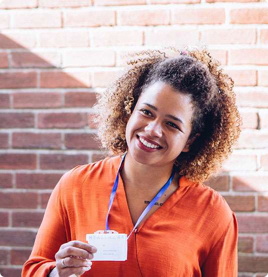 Caregiver holding ID badge, smiling.